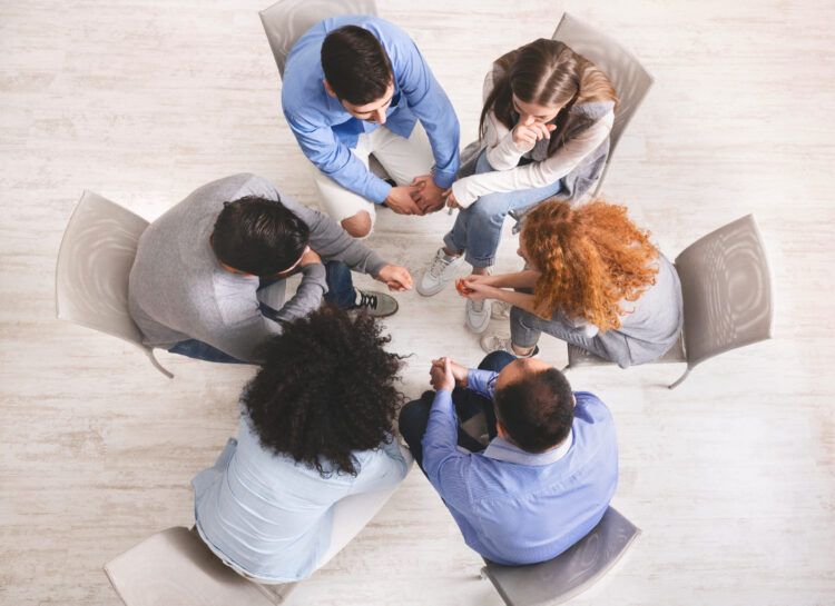 Group of individuals in a support circle participating in a 12 Step Program, focusing on healing and recovery.