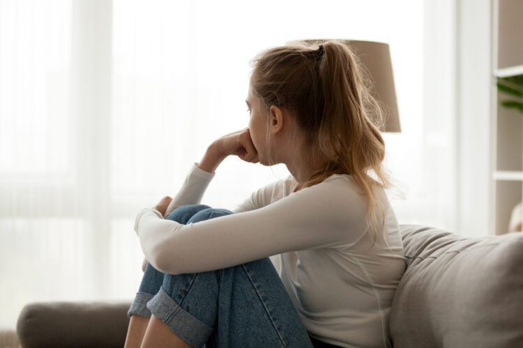 An individual sitting thoughtfully on a couch, contemplating recovery, symbolizing the journey through Drug Rehab in Tennessee.